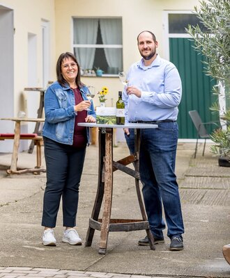 The hosts of the Haus in the courtyard, welcoming guests with a glass of wine.