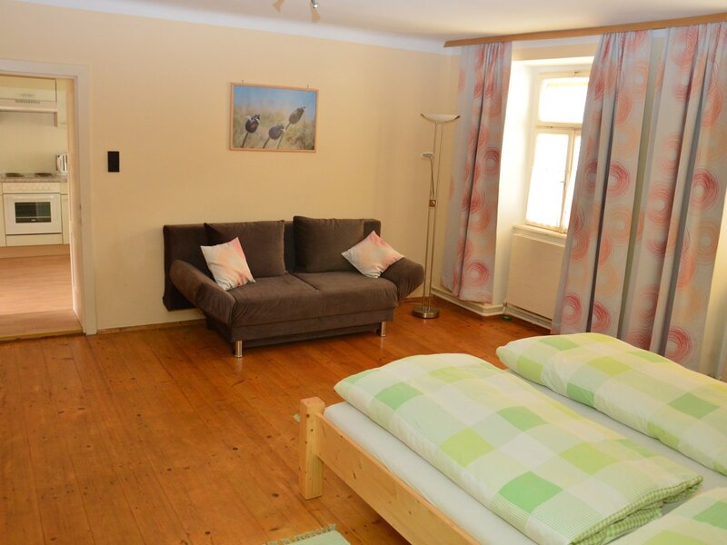 The combined living and sleeping area of the farmhouse, featuring a double bed, a sofa, and an adjacent kitchen.
