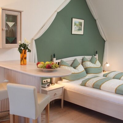 Double bedroom in the farmhouse featuring a bar table with two stools, a sloping ceiling, and a nightstand.