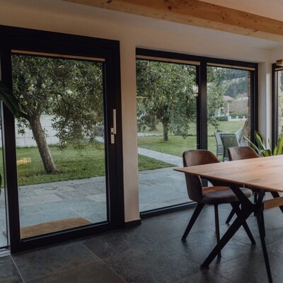 Dining area in the chalet with large glass fronts and a view of the orchard.