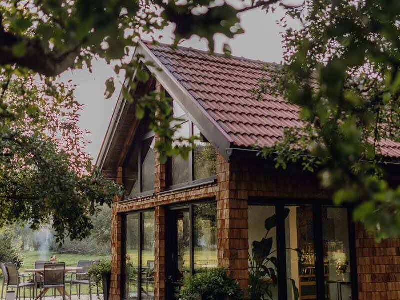 The cozy orchard chalet of the farmhouse, featuring a paved terrace and large glass windows.