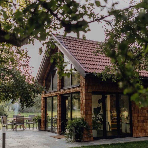 The cozy orchard chalet of the farmhouse, featuring a paved terrace and large glass windows.
