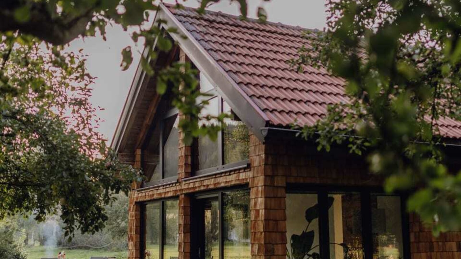 The cozy orchard chalet of the farmhouse, featuring a paved terrace and large glass windows.