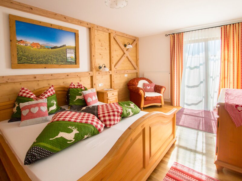 Bedroom in the Farm House featuring a wooden bed, traditional bedding, an armchair, and access to a balcony.