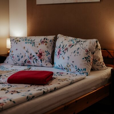 Bedroom in the Farm House featuring a bed with floral patterned bedding and two bedside lamps.