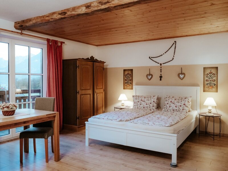 Double bedroom in the farm house featuring a wardrobe, dining table, and balcony access with mountain views.
