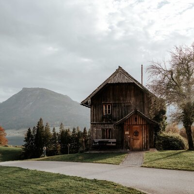 The farm house exterior, featuring traditional wooden architecture, set against a backdrop of mountains and Lake Wolfgangsee.