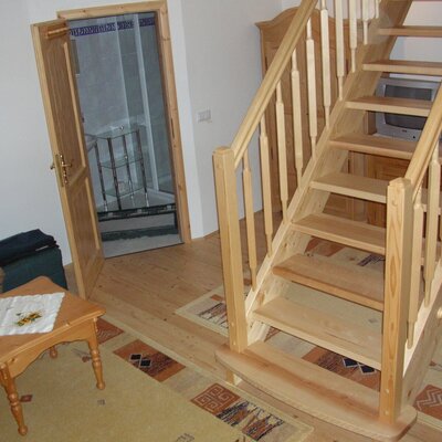 The Farm House features a wooden staircase and an adjacent living area, with a shower accessible through the doorway.