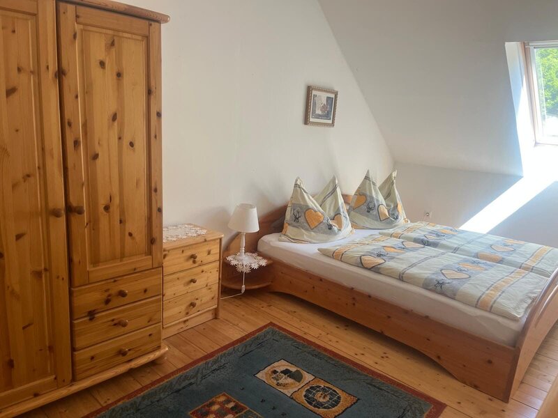 Bedroom in the farmhouse with a double bed, wooden wardrobe, and window.