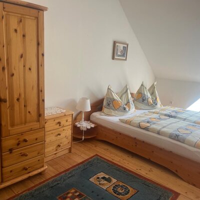 Bedroom in the farmhouse with a double bed, wooden wardrobe, and window.