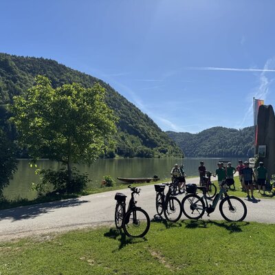 Bicycles and a group of cyclists by the lakeside, highlighting the Bauernhof's bike-friendly environment and Radgarage.