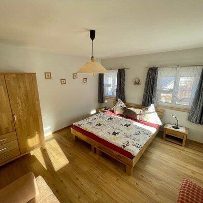 A double bedroom in the Farm House, equipped with a wooden wardrobe, two windows, and bedside tables.