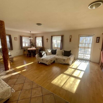 Combined living and dining area in the farm house, featuring a sofa, a dining table, and balcony access.