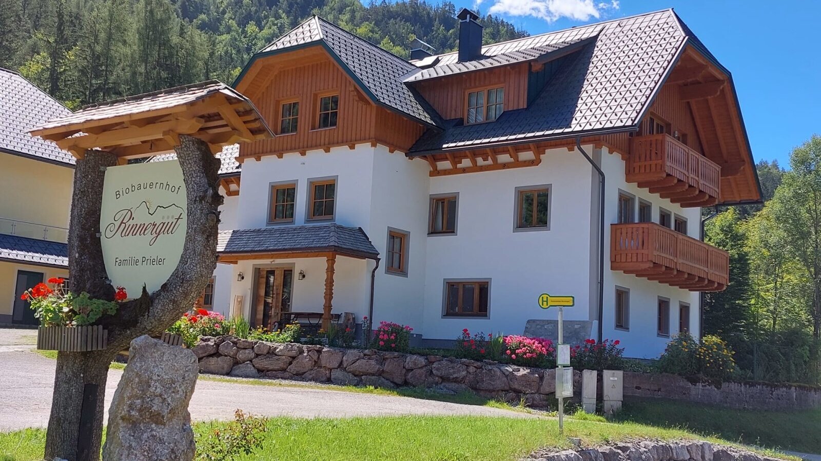 Exterior view of the Rinnergut Bauernhof, featuring wooden balconies and the 'Biobauernhof Rinnergut Familie Prieler' sign.