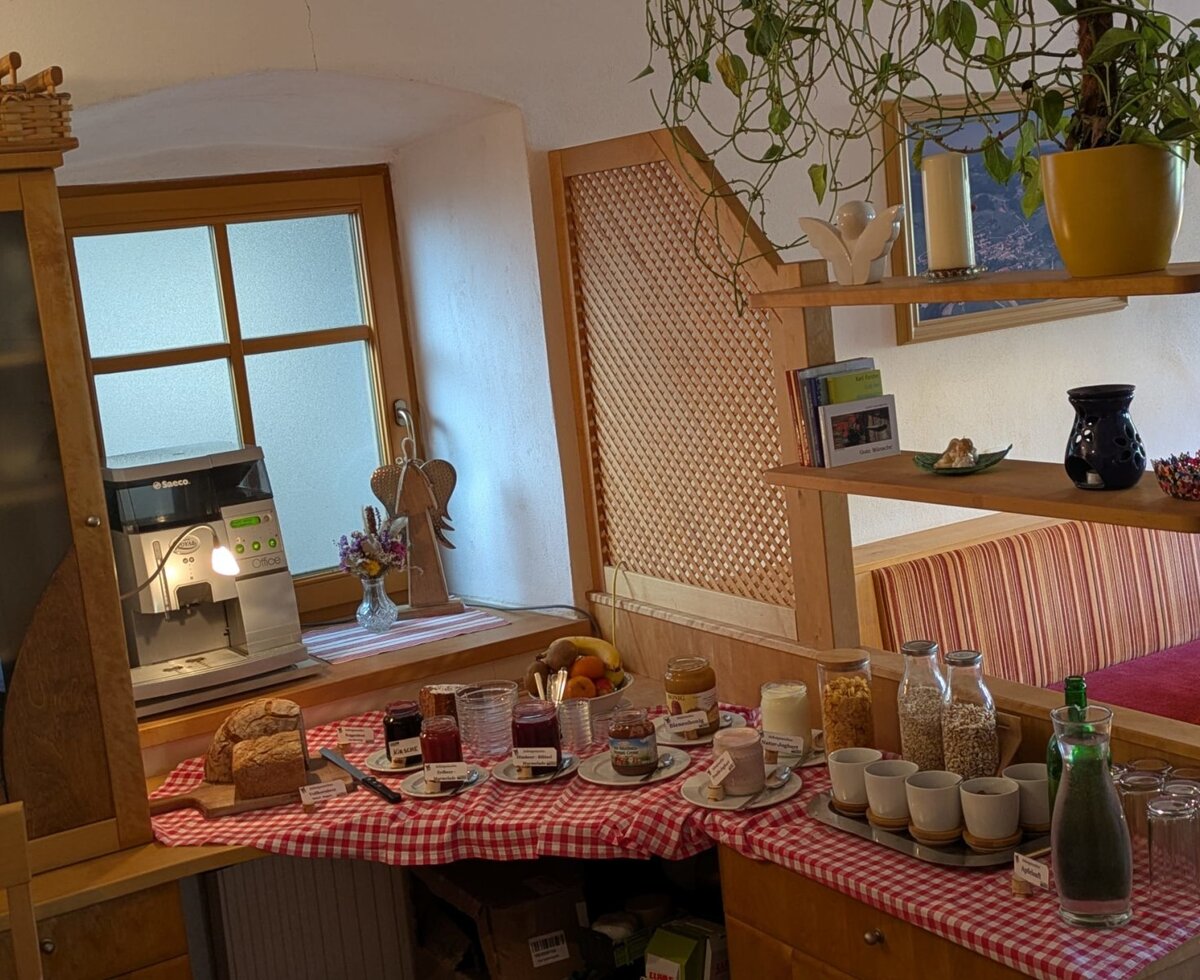 Breakfast buffet at the farmhouse with fresh bread, jams, yogurt, muesli, and a coffee machine.