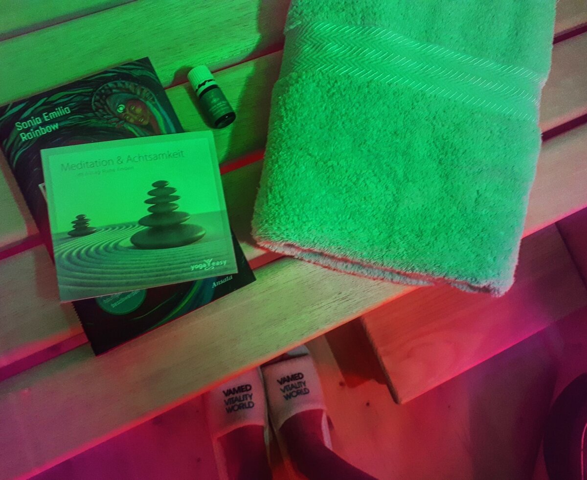 The farmhouse's sauna features a wooden bench with a towel, meditation books, and essential oils.