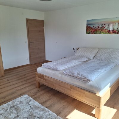 Double bedroom in the farm house featuring a wooden bed, two nightstands with reading lights, and a wardrobe.