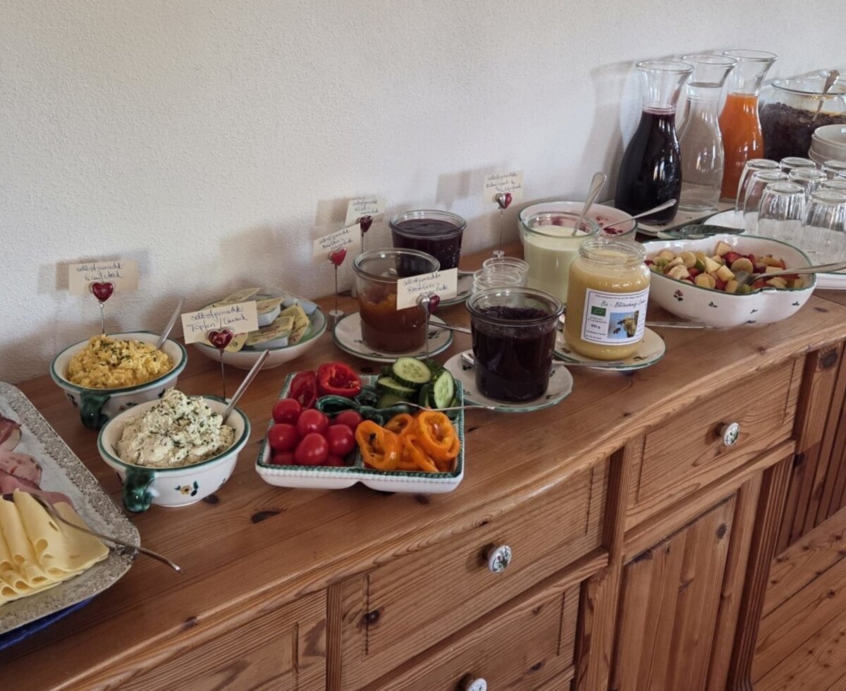 The rich farm breakfast at the mountain farm with cold cuts, cheese, scrambled eggs, spreads, fresh vegetables, fruit salad, muesli, juices, and homemade products.