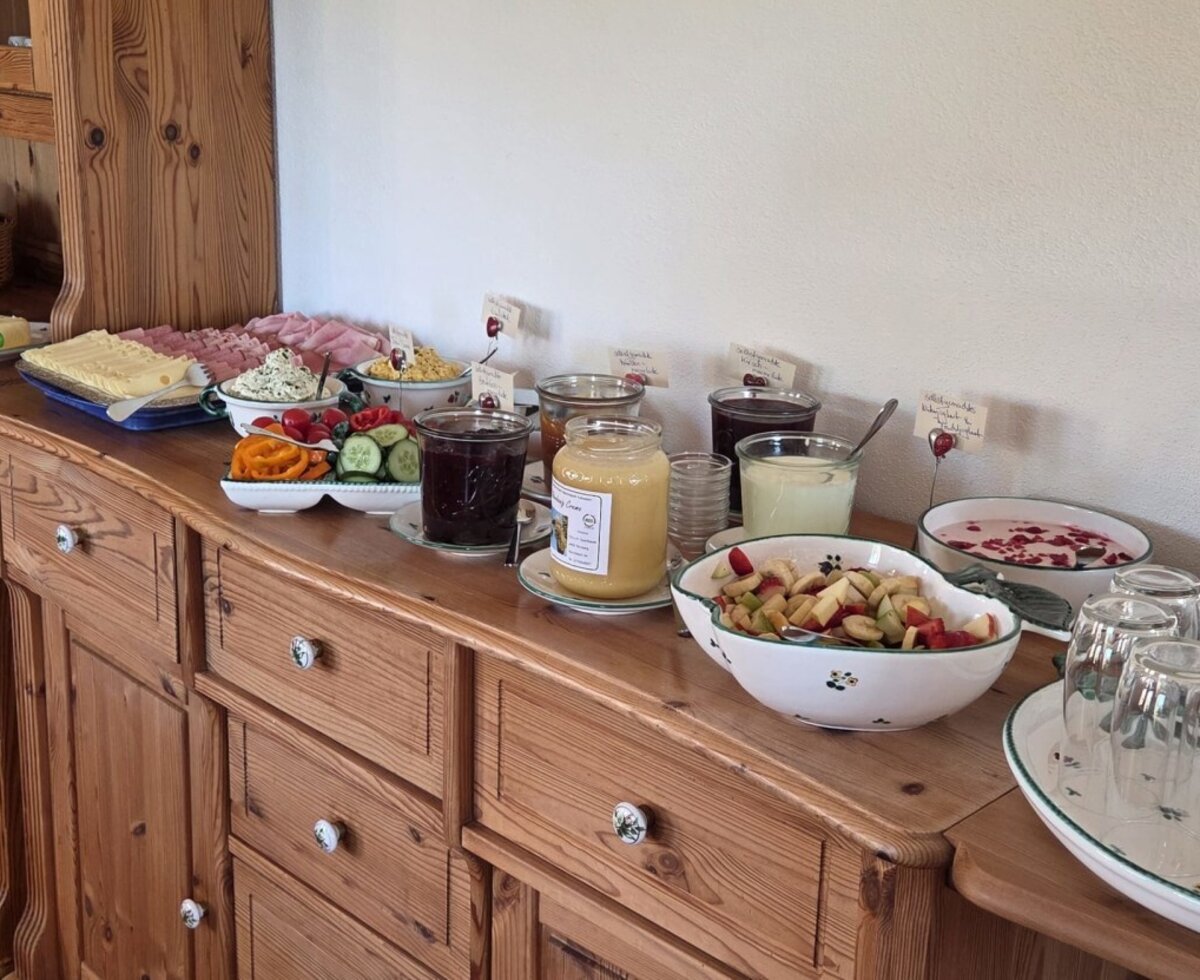 The rich farmhouse breakfast of the Bauernhof, featuring bread, cold cuts, homemade jams, and fresh fruit salad.