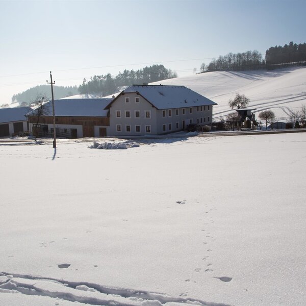 The farm house and its buildings are situated in a snow-covered winter landscape with fields and hills. The farm house and its buildings are situated in a snow-covered winter landscape with fields and hills.