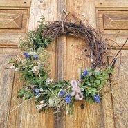 An inviting, handcrafted wreath with fresh spring flowers on a wooden door welcomes guests to the apartment.
