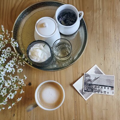 An inviting arrangement in the apartment featuring a fresh cup of coffee, delicate white flowers, and a decorative tray on a wooden table.