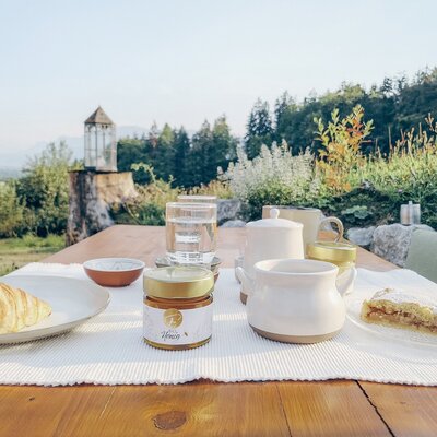 An inviting outdoor breakfast table set with fresh pastries and organic honey against the farmhouse's scenic natural backdrop.