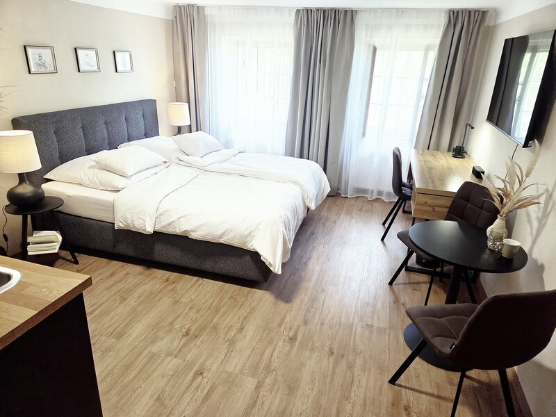 The apartment's inviting bedroom with a comfortable double bed, wooden flooring, and a cozy seating area.