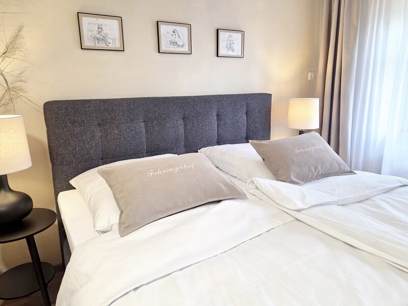 A cozy double bed in the apartment with inviting linens, stylish bedside lamps, and warm lighting.