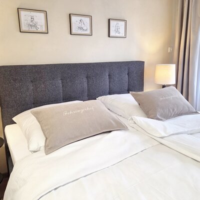 A cozy double bed in the apartment with inviting linens, stylish bedside lamps, and warm lighting.