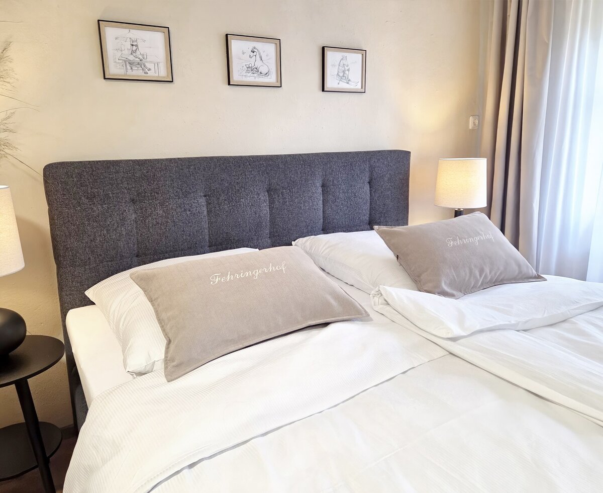 A cozy double bed in the apartment with inviting linens, stylish bedside lamps, and warm lighting.
