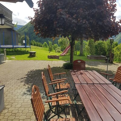 One of the three terraces at the Farm House, furnished with a dining table and chairs, overlooking the outdoor play area.
