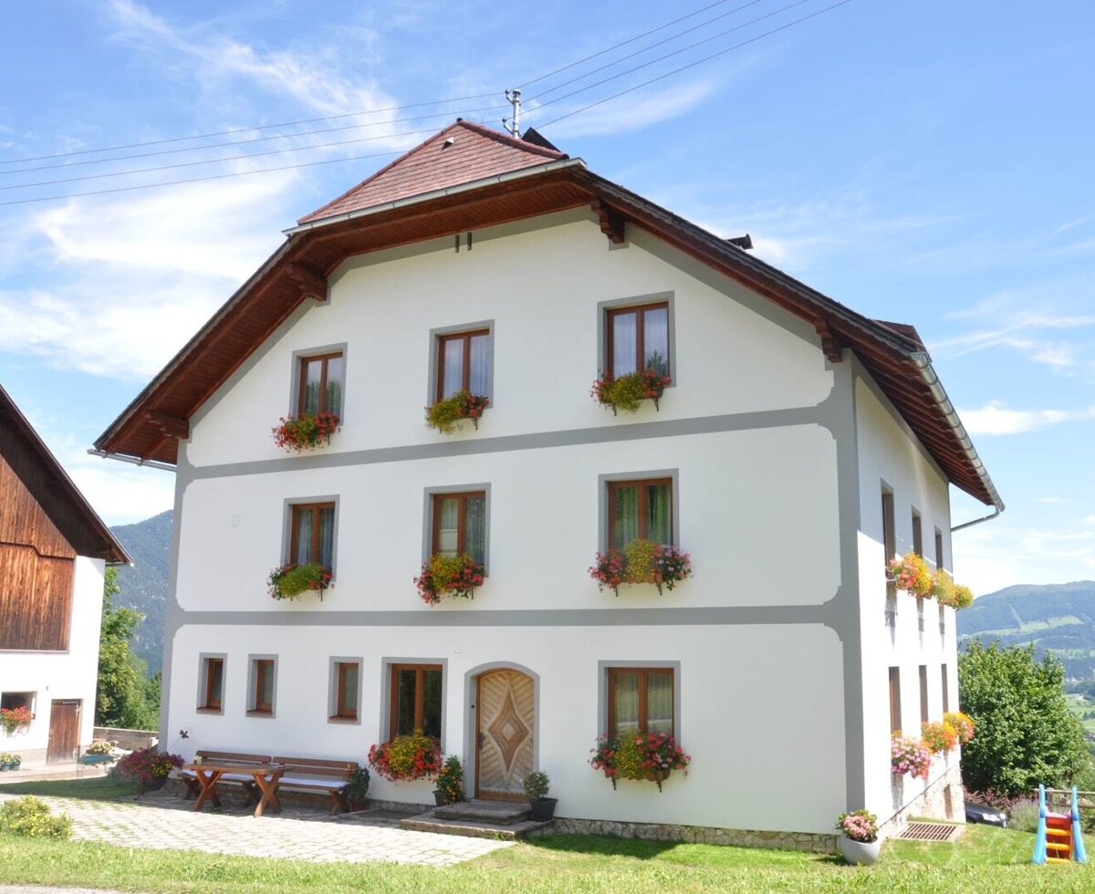 The Farm House exterior features windows with flower boxes, outdoor benches, a children's slide, and views of the surrounding mountains.