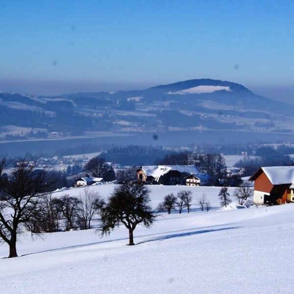 The winter landscape surrounding the Farm House, featuring snow-covered hills, a lake, and distant mountains.