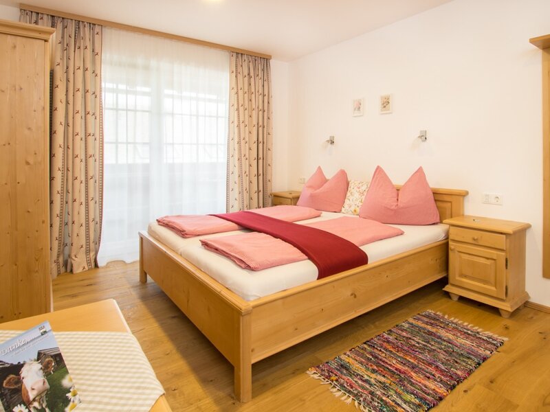 Farm house double bedroom with a wooden bed frame, two bedside tables, a wardrobe, and a window providing natural light.