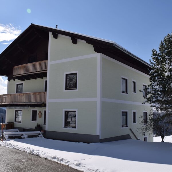 The farm house exterior, featuring a light green facade, multiple wooden balconies, and a snow-covered environment. The farm house exterior, featuring a light green facade, multiple wooden balconies, and a snow-covered environment.