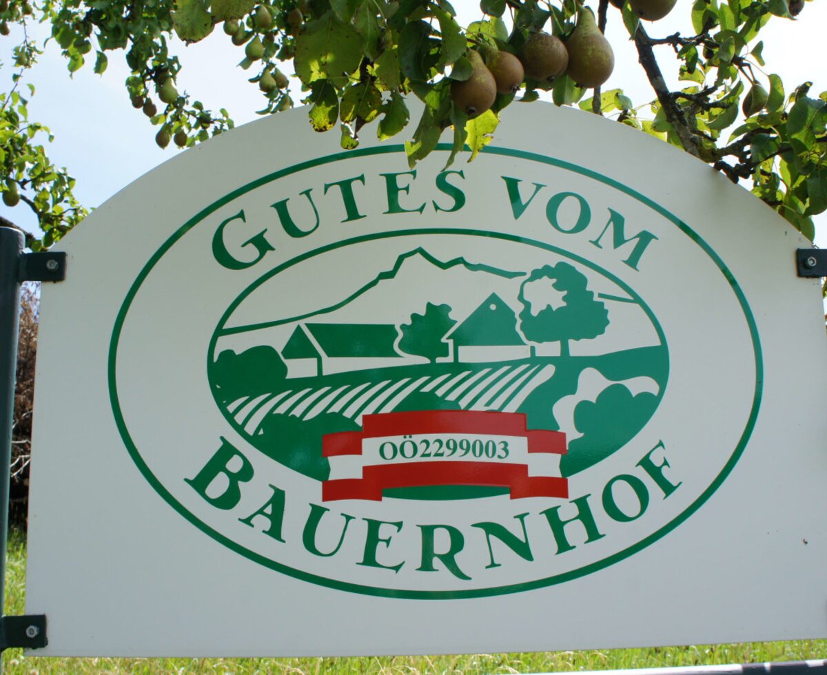 The farmhouse sign, displaying 'Gutes vom Bauernhof' (Goods from the Farm), is visible under a pear tree.