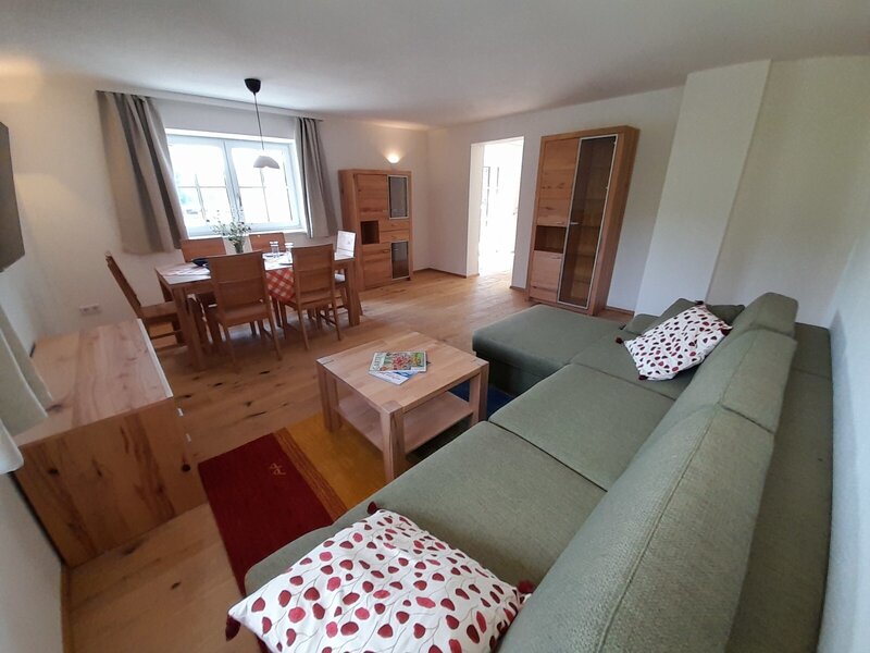 The farm house offers a combined living and dining area with a sectional sofa, a wooden coffee table, and a dining table with chairs.