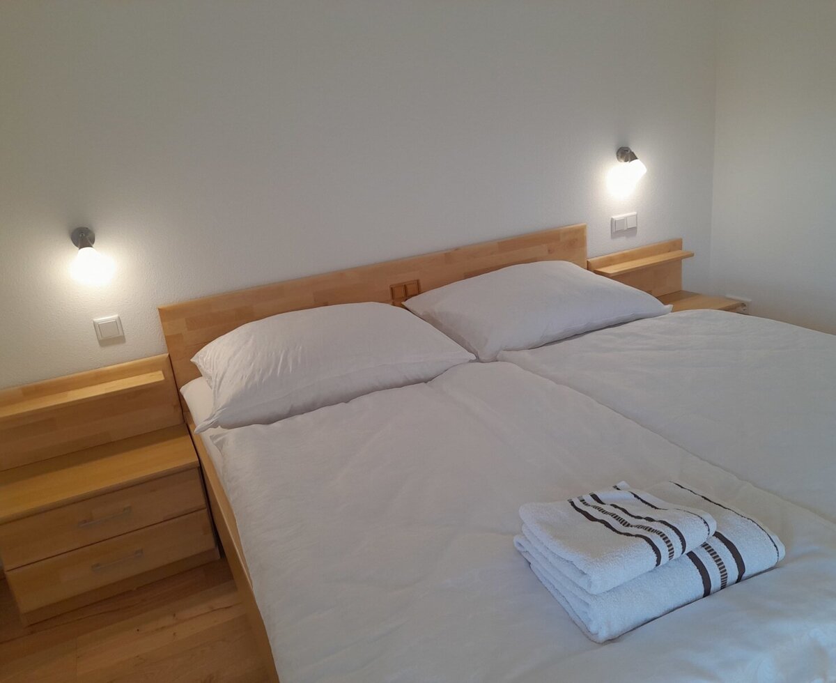 Double bedroom in the Farm House featuring a double bed with two individual duvets, wooden bedside tables, and reading lights.