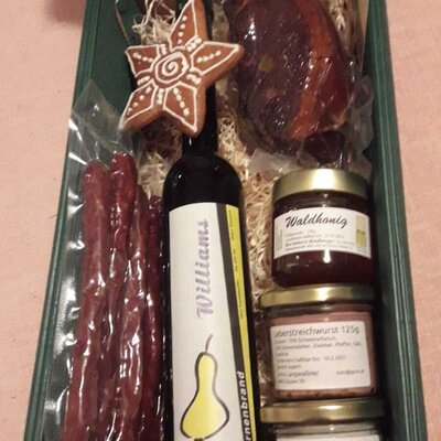 A welcoming gift box from the farm house, featuring pear brandy, sausages, cured meat, honey, liver spread, crackling lard, and a gingerbread cookie.