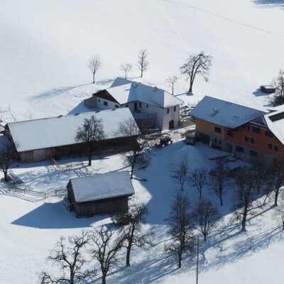 Aerial view of the farmhouse property, featuring several buildings nestled within a snow-covered rural landscape.