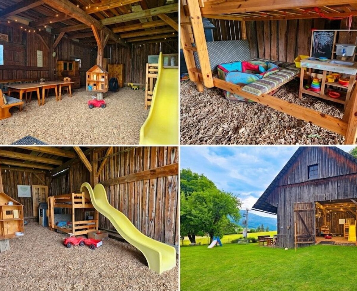 The indoor play area at the farmhouse features a slide, a play kitchen, a dollhouse, and seating on a wood chip floor.