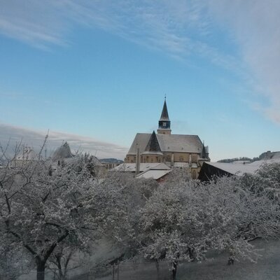 Winter view of the church and snow-covered trees in the surroundings of the farmhouse.