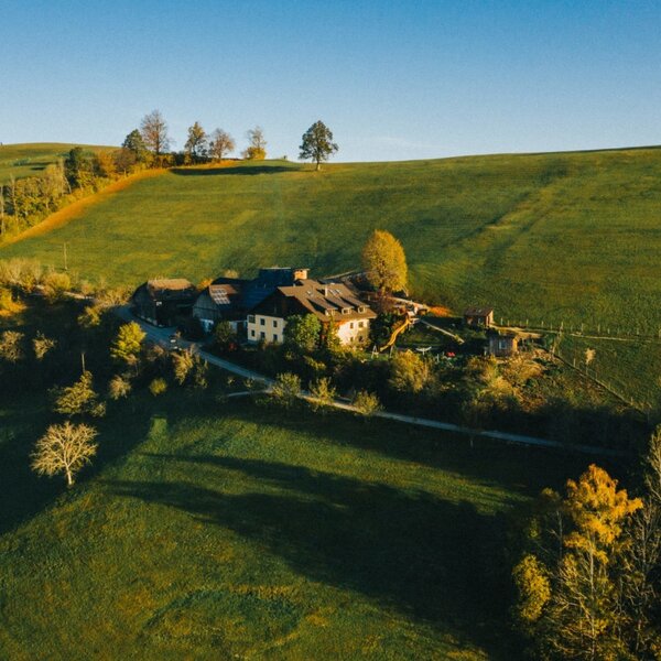 Aerial view of the farmhouse, surrounded by green hills and trees