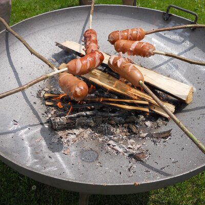 Knackwurst on grill sticks over an open fire of a grill tray.