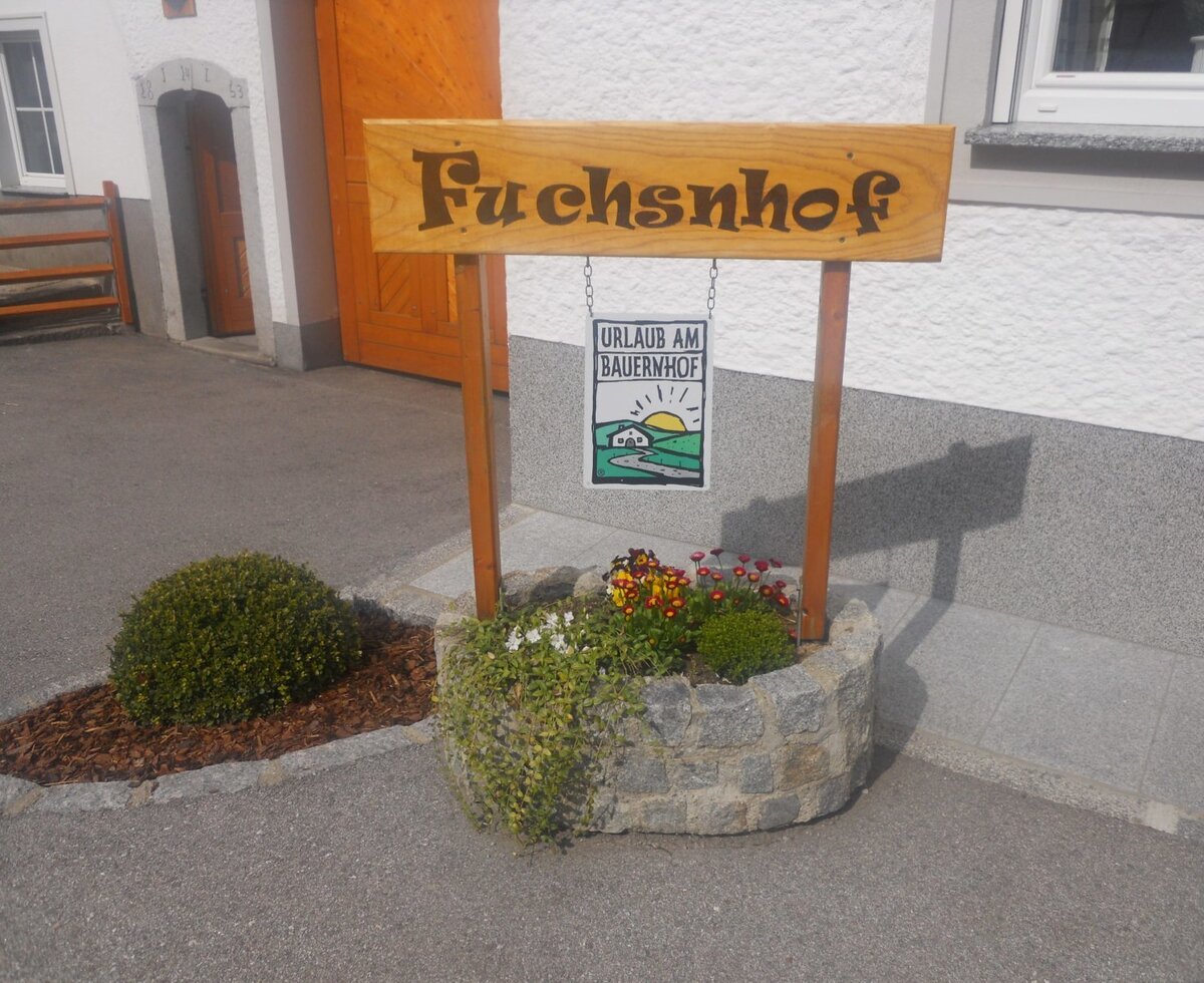 Wooden welcome sign with Fuchsnhof and farm holidays.