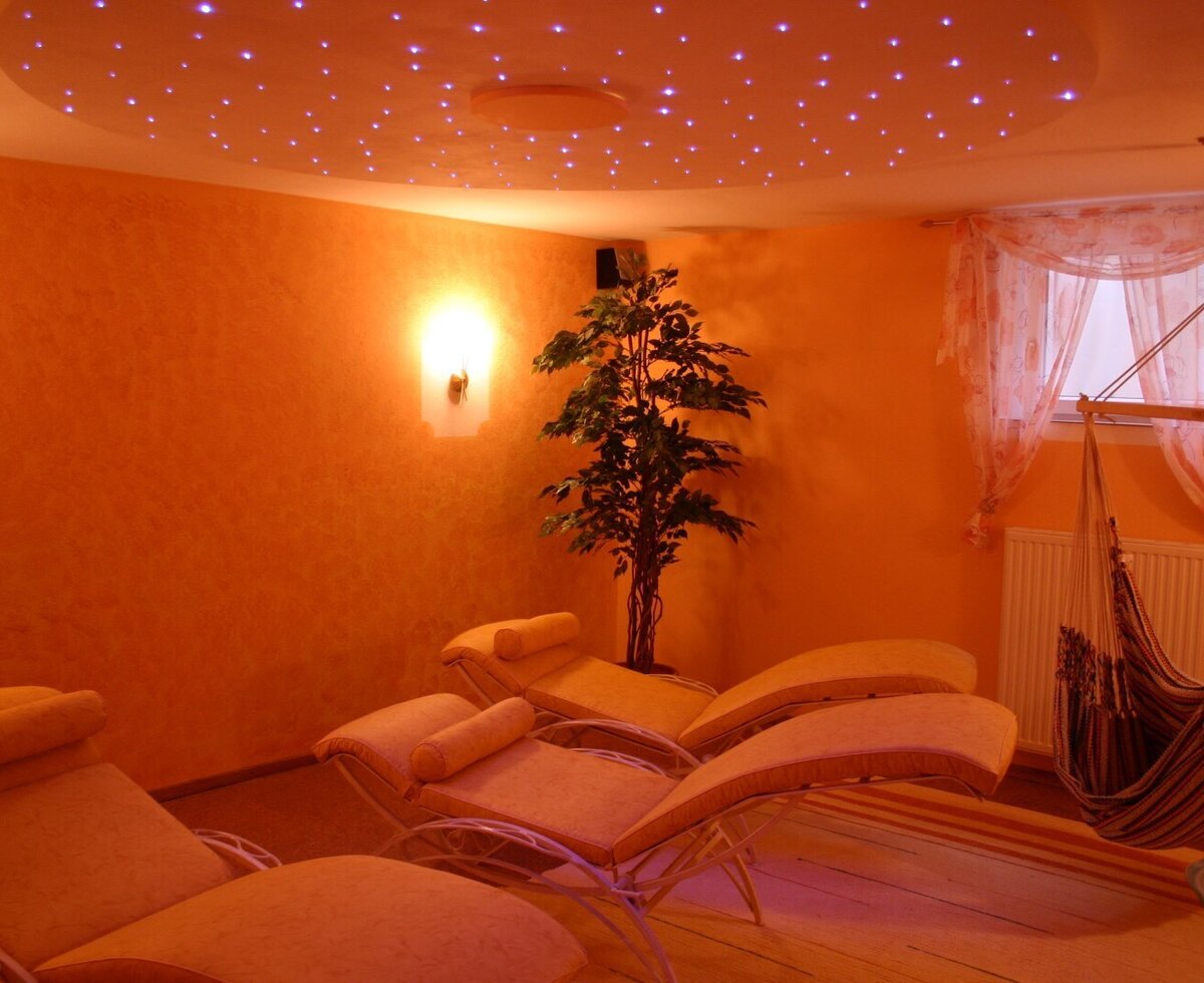 A room in the Farm House equipped with lounge chairs, a hanging hammock, and a ceiling with fiber optic star lights.