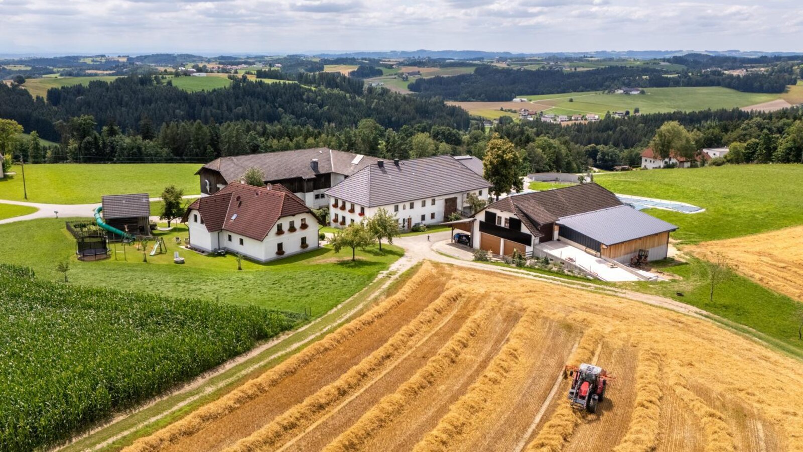 Aerial view of the farmhouse with its buildings, a tractor in the fields, and a playground. ©TVB Mühlviertel Berlinger Justin