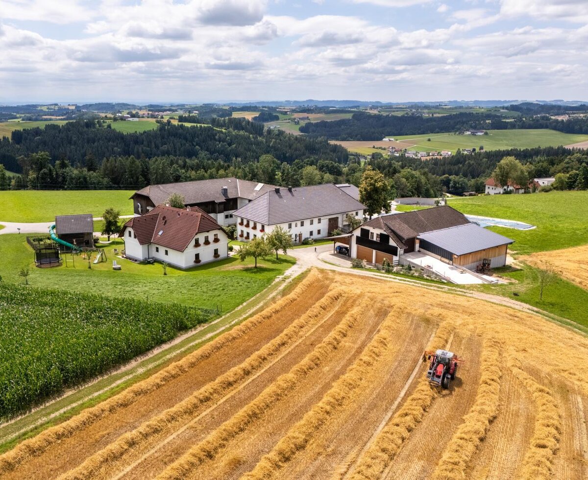 Aerial view of the farmhouse with its buildings, a tractor in the fields, and a playground. ©TVB Mühlviertel Berlinger Justin