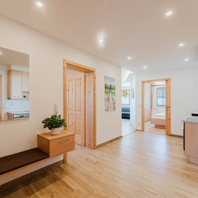 A bright and welcoming entrance area in the farmhouse, featuring a cozy bench and warm wooden accents.